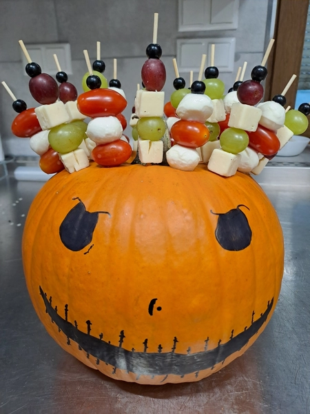 Vital Scheunep – Catering Grillwagen Geschirrverleih – kreative Halloween-Speisenpräsentation mit Obst- und Käsespießen in einem dekorierten Kürbis.